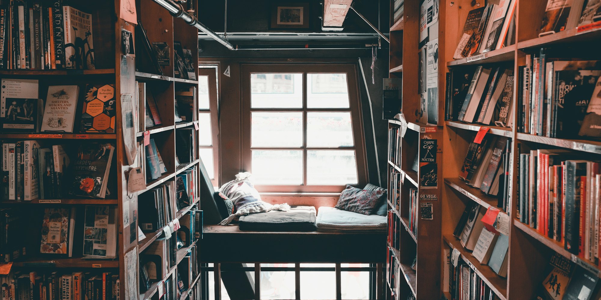 A window seat tucked between tall wooden bookshelves